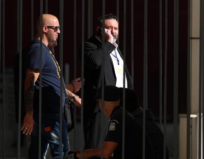 European Parliament member Ioannis Lagos, center, who had been found guilty along with others of leading a criminal organisation, and face five to 15 years in prison, uses his mobile phone outside a court, waiting for his sentencing in Athens AP
