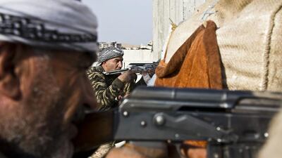 Fighters from the Free Syrian Army, left, and the Kurdish People's Protection Units (YPG), center, join forces to fight ISIL in Kobani on November 19. Jake Simkin / AP