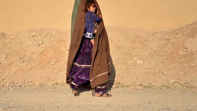 A woman carrying a child walks along a roadside in Kandahar province, Afghanistan. AFP