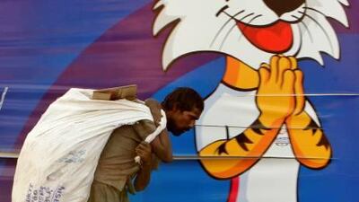 Shamshul carries recyclable trash he scavenged from the roadside against the backdrop of the Commonwealth Games mascot Shera in New Delhi.