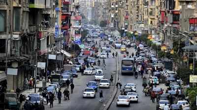 Cars pedestrians are pictured in one of the Egyptian capital Cairo's popular streets, shortly before the first day of a two-weeks night-time curfew imposed by the authorities to contain the spread of the novel coronavirus on March 25, 2020. AFP