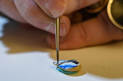 Turkey's micro artist Hasan Kale paints on a broad bean in Istanbul on August 23, 2019. His canvas could be anything from match sticks, seeds to razors and crown corks. Turkey's micro artist, also known as Turkish Microangelo in reference to Italian Renaissance sculptor and painter Michelangelo, has been hitting his brush onto tiny everyday objects for more than two decades. - RESTRICTED TO EDITORIAL USE - MANDATORY MENTION OF THE ARTIST UPON PUBLICATION - TO ILLUSTRATE THE EVENT AS SPECIFIED IN THE CAPTION / AFP / Ozan KOSE / RESTRICTED TO EDITORIAL USE - MANDATORY MENTION OF THE ARTIST UPON PUBLICATION - TO ILLUSTRATE THE EVENT AS SPECIFIED IN THE CAPTION