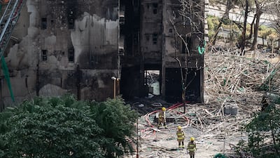 Firefighters walk through burnt buildings after the deadly fire. AP
