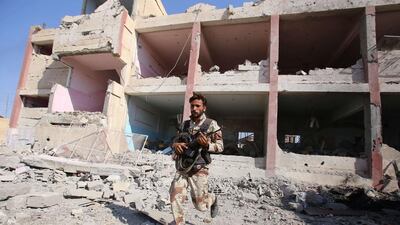 A member if the Syrian regime forces runs near destroyed buildings in the northeastern Syrian city of Hasakeh. Youssef Karwashan / AFP