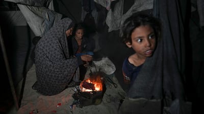 Shireen Daifallah, who was displaced with her children from northern Gaza, checks the fire next to their tent at a camp in Deir Al Balah. AP