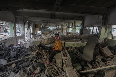 A Palestinian boy sits at the destroyed building of the Fahmi Al Jarjawi school following the Israeli air strike. EPA