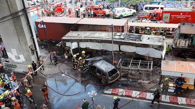 Rescue workers extinguish a fire in the wreckage of a bus after it was hit by a freight train near Makkasan station in Bangkok. EPA