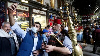 Ishaaq Kremed, a tamarind juice seller, poses for a picture with a customer in Hamidiyah Souq, Damascus. AFP