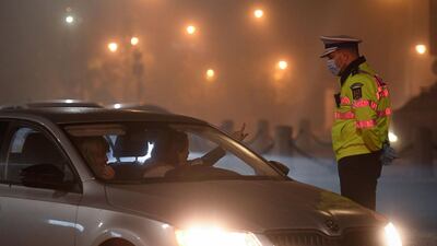 A Romanian policeman explains the newly instated curfew to a driver showing his identity card through the car window in Bucharest. AFP