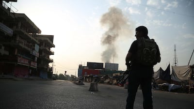 An Afghan security official stands guard as smoke billows from a prison after a militant attack in Jalalabad, Afghanistan. EPA