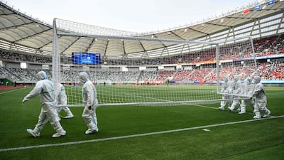 Workers wearing PPE carry a goalpost ahead of an Olympic Games qualifier match for the women's football tournament between China and South Korea at Suzhou Olympic Sports Centre Stadium, Suzhou, Jiangsu province, China. AFP