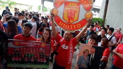 Manchester United football fans hold posters as the team in Thailand.