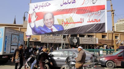 Egyptians walk underneath an election campaign banner erected by supporters of Egyptian President Abdel Fattah El Sisi in Cairo. Khaled Elfiqi / EPA