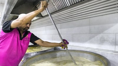 A cook stirs a pot filled with aromatic broth and broken rice to make the kanji.