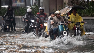 Motorists commute along a flooded street after heavy rain in Manila. AFP