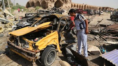 Civilians inspect the aftermath of a suicide car bombing at a busy market in Khan Bani Saad near Baghdad that killed at least 80 people gathered to mark Eid Al Fitr. Karim Kadim / AP