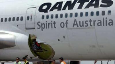 Workers and security personnel stand next to the hole of the Melbourne-bound Qantas Boeing 747 after it made an emergency landing in Manila.