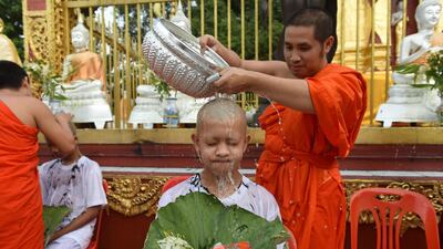 A monk bathes the shaved head of the rescued boy. AFP