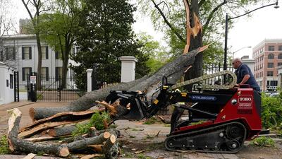 A state grounds engineer uses a mini skid steer to remove some of the limbs and trunk from this downed tree that was felled by strong winds on the grounds of the Mississippi Governor's Mansion on to a main intersection of central Jackson. AP