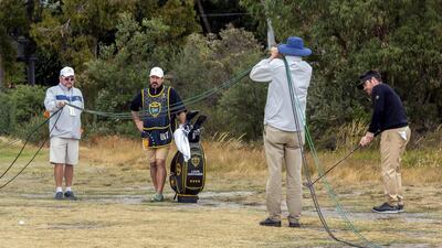 International team player Louis Oosthuizen hits to the green as staff hold cables out of the way. AFP