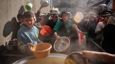 Palestinians wait to receive donated food at a community kitchen in central Gaza. AP