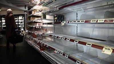 A woman stands next to an empty shelf in a supermarket in Paris a day after France ordered the closure of all non-essential public places including restaurants and cafes. AFP