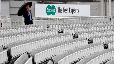 A spectator shelters from the rain with an umbrella ahead of play. AFP