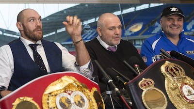Newly crowned heavyweight world boxing champion Tyson Fury, left, getures as he sits alongside his uncle and trainer Peter Fury, centre, and his father John Fury at a media day in Bolton, England, Monday, Nov. 30, 2015. (AP Photo/Jon Super)