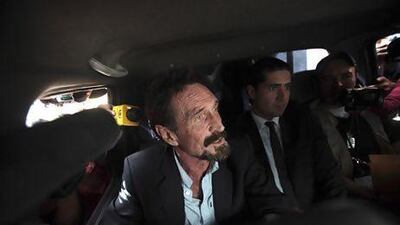 John McAfee, left, is escorted by immigration officers in Guatemala City at the city's airport on December 12. William Gularte / Reuters