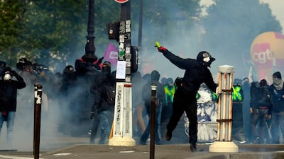 A protestor throws a missile towards police as teargas clouds rise. AFP/ALAIN JOCARD