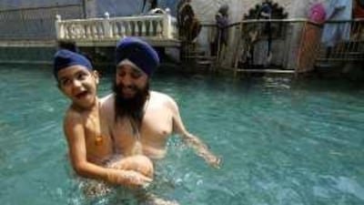 A Pakistani Sikh and his son wade in the holy water of Panja Sahib shrine in Hasanabdal.
