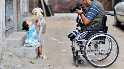 Moamen Qreiqea takes pictures of his daughter outside his home in Gaza City.