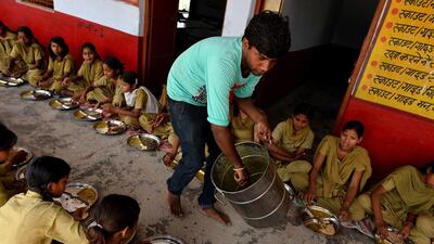 A man serves lunch, organised by the non-profit Akshaya Patra Foundation, to schoolgirls at the Chaumuha Primary School.