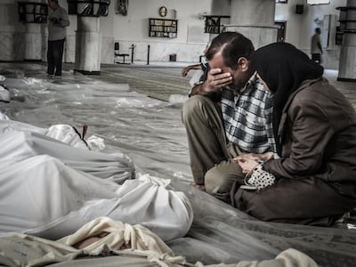A mother and father weep over the body of their child, who was killed in a suspected chemical weapons attack in the Damascus suburb of Ghouta. AFP