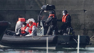 Border Force officers with men thought to be migrants, wearing face masks as they come to shore in Dover, south England. AP