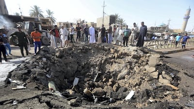 Iraqi men look at a crater left by a massive suicide car bomb attack carried out the previous day by ISIS in the predominantly Shiite town of Khan Bani Saad, 20km north of Baghdad, on July 18, 2015. AFP