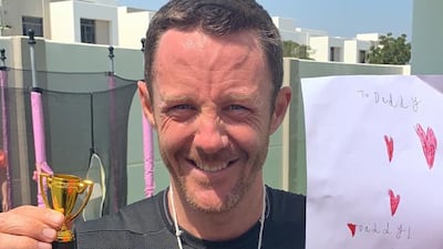 Adidas runners captain Lee Ryan shows off the drawing and trophy his daughters gave him for completing his backyard marathon. Courtesy Lee Ryan