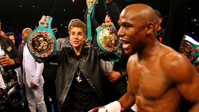 Singer Justin Bieber holds up a belt for Floyd Mayweather Jr before Mayweather Jr.takes on Miguel Cotto during their WBA super welterweight title fight at the MGM Grand Garden Arena on 5 May, 2012 in Las Vegas. Al Bello / Getty Images / AFP