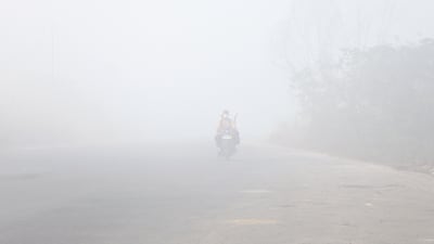 A motorcyclist wearing a face mask rides through thick haze from wildfires in Banyuasin, South Sumatra, Indonesia. EPA