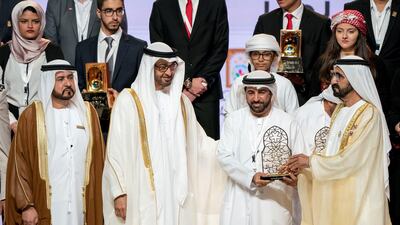 Sheikh Mohammed bin Zayed, Crown Prince of Abu Dhabi and Deputy Supreme Commander of the UAE Armed Forces, third right, and Sheikh Mohammed bin Rashid, Vice President and Ruler of Dubai, right, present an award to a winner during the Sheikha Fatima bint Mubarak Awards for Excellence and Social Creativity, at Emirates Palace. They are seen with Ali bin Salem Al Kaabi, Director of the Office of the Minister of Presidential Affairs and Chairman of the Board of Trustees of the Family Development Foundation, left. Rashed Al Mansoori / Crown Prince Court - Abu Dhabi