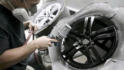 A mechanic sprays a repaired alloy rim at Monza car detailing workshop. Antonie Robertson / The National