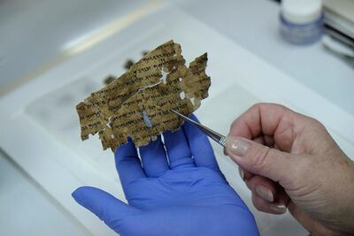 A worker of the Israeli Antiquity Authority sews fragments of the Dead Sea scrolls which includes biblical verses in a preservation laboratory of the Israel Museum in Jerusalem. Getty Images