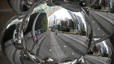 Financial district buildings are reflected on a metal ball sculpture in Singapore. Singapore's economic growth slowed sharply in the first three months of the year, data showed, but the central bank stood pat on monetary policy saying it would be lifted by a pick-up in global growth. ROSLAN RAHMAN / AFP