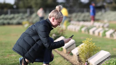 A woman takes a picture of a grave stone as people attend the Australian Memorial Service for Anzac Day on the Gallipoli Peninsula, Turkey. EPA