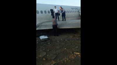 A flight attendant speaks to an onlooker as passengers use a wing of the crashed plane to reach safety. AP