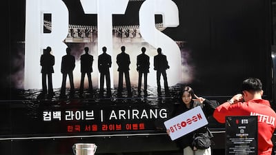 A woman poses for a photo in front of a truck promoting the comeback concert of K-pop group BTS in Seoul. AFP
