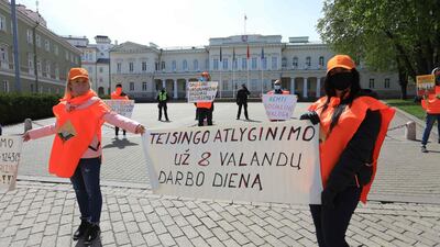 Members of the Lithuanian Trade Union "Solidarity", wearing protective masks and respecting the social distancing rules against the spread of the novel coronavirus, COVID-19, protest in front of the Lithuanian Presidential Palace during the Labour Day demonstration in Vilnius the poster reads "Equitable remuneration for the 8-hour day". AFP