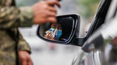 A woman in a car shows a company identification card for verification by a Philippine Army soldier to enter a quarantine border of Quezon City, Metro Manila. EPA