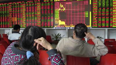Investors look at an electronic board showing stock information at a brokerage house in Haikou, Hainan province of China. Reuters