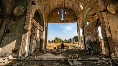A member of the Khabour Guards (MNK) Assyrian Syrian militia, affiliated with the Syrian Democratic Forces (SDF), sits in the ruins of the Assyrian Church of the Virgin Mary, which was previously destroyed by ISIS fighters, in the village of Tal Nasri south of the town of Tal Tamr in Syria's northeastern Hasakah province. AFP